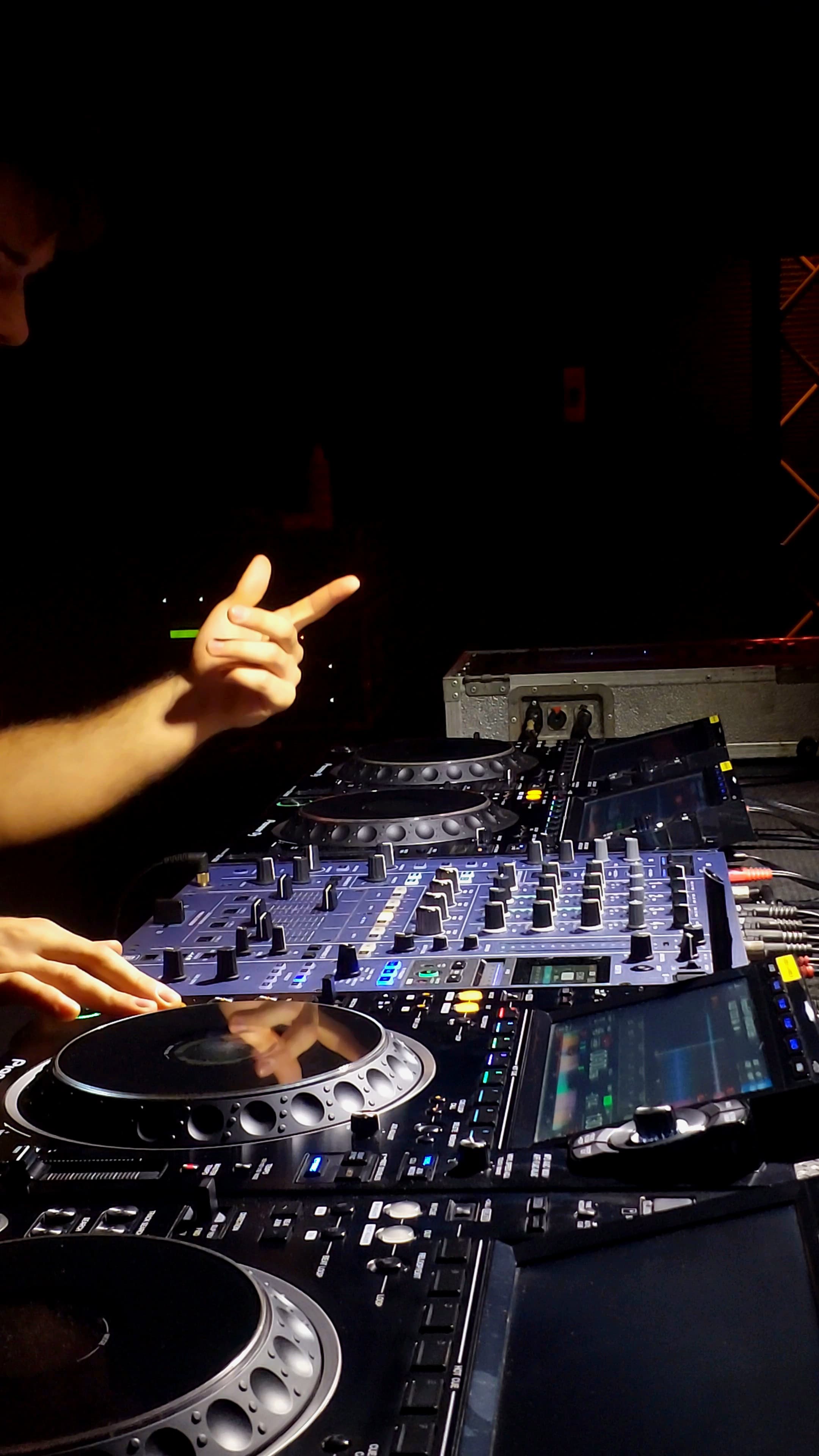 FRIXX performing over professional DJ decks and gesturing with one hand.